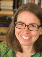 A photo of Jodie - a smiling white woman with glasses and shoulder-length brown hair
