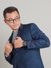 A headshot of Kevin, a light-skinned man in his 30s with short hair and full-framed glasses, smiling shyly with a sideways glance