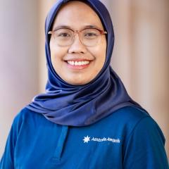 A headshot of Lisa – a women with hijab and glasses in front of the university building