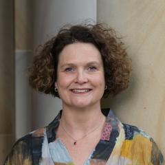 A headshot of Shannon Breen – a white woman with short brown hair standing in the Great Court at UQ